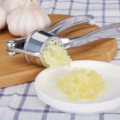 Stainless steel garlic press crushing garlic cloves into a dish, showcasing easy cleanup and effective mincing.
